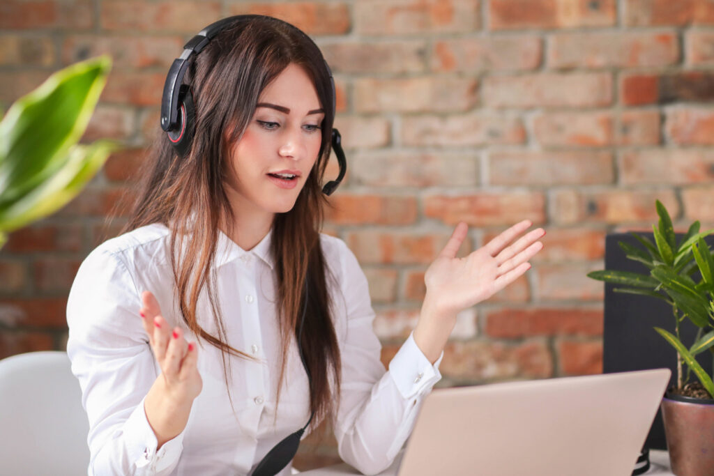 a woman wearing headphones looking at a laptop screen offering virtual assistant services