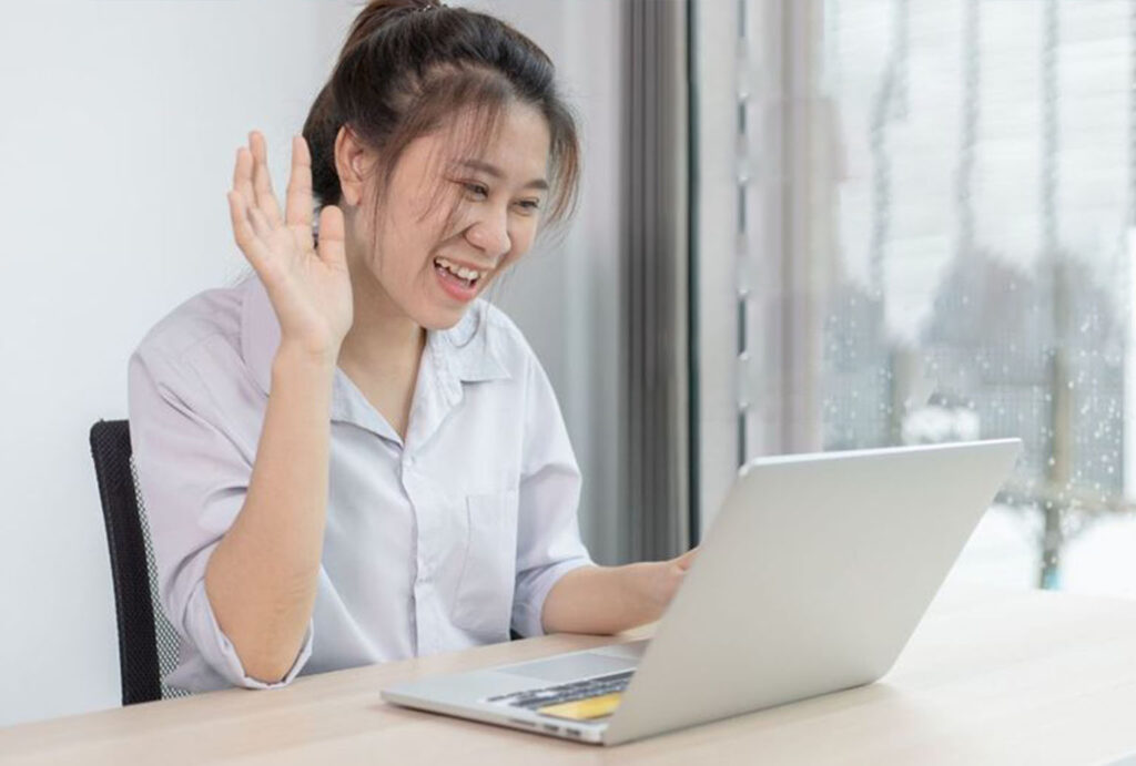 a woman waving at a laptop applying as a Virtual Assistant