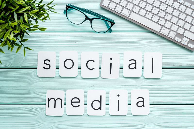 a keyboard and glasses on a blue wooden surface for advertising social media