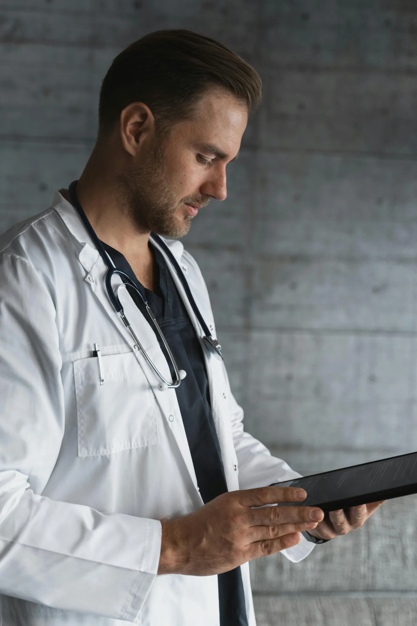 Physician in a white coat reviewing patient information on a tablet
