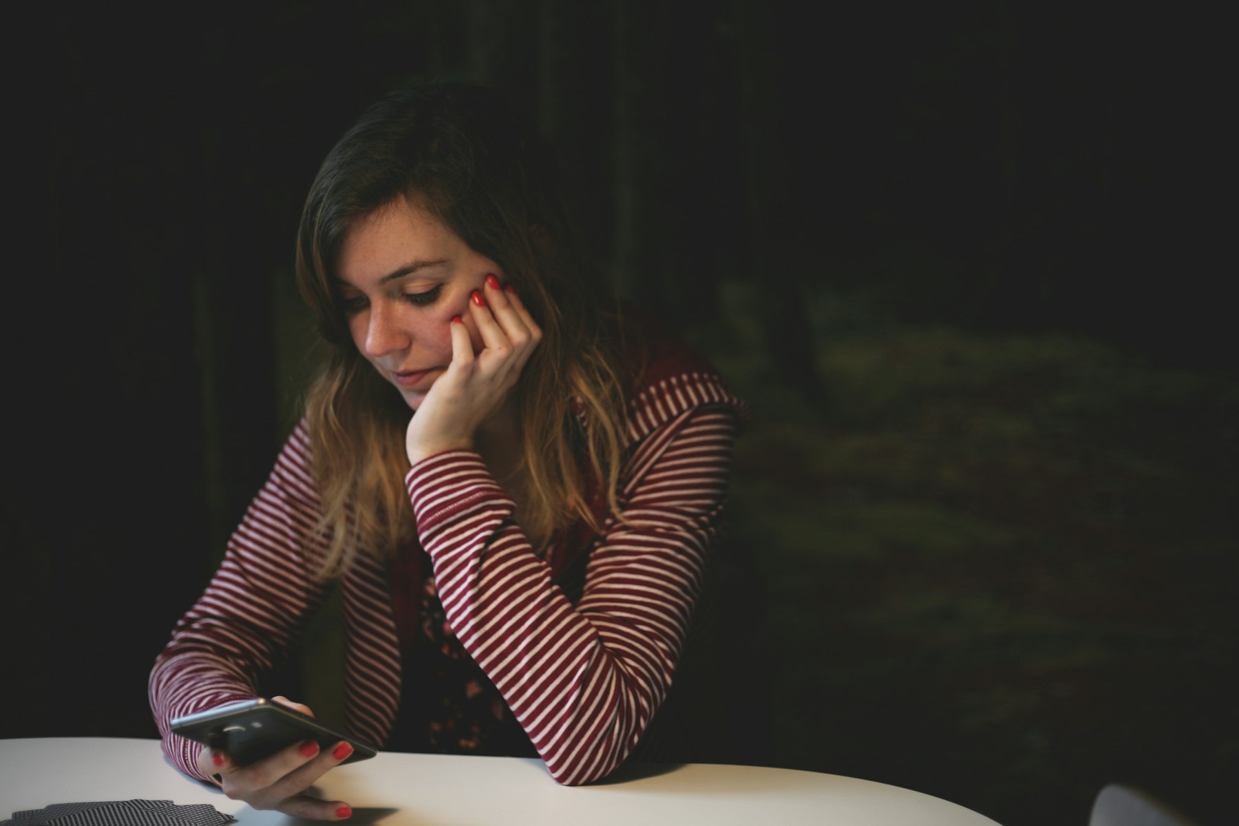 Woman seated at a table reading an AI assistant chat on her smartphone