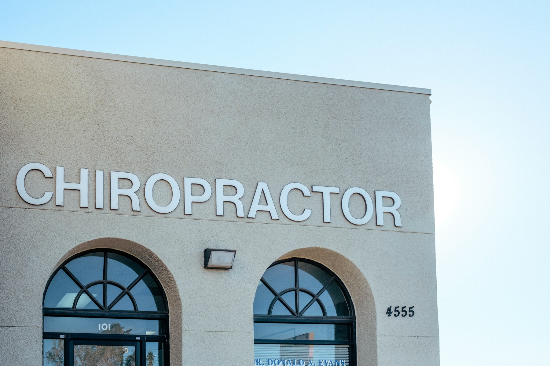 Exterior of a chiropractic office with two arched windows and a sign that reads Chiropractor