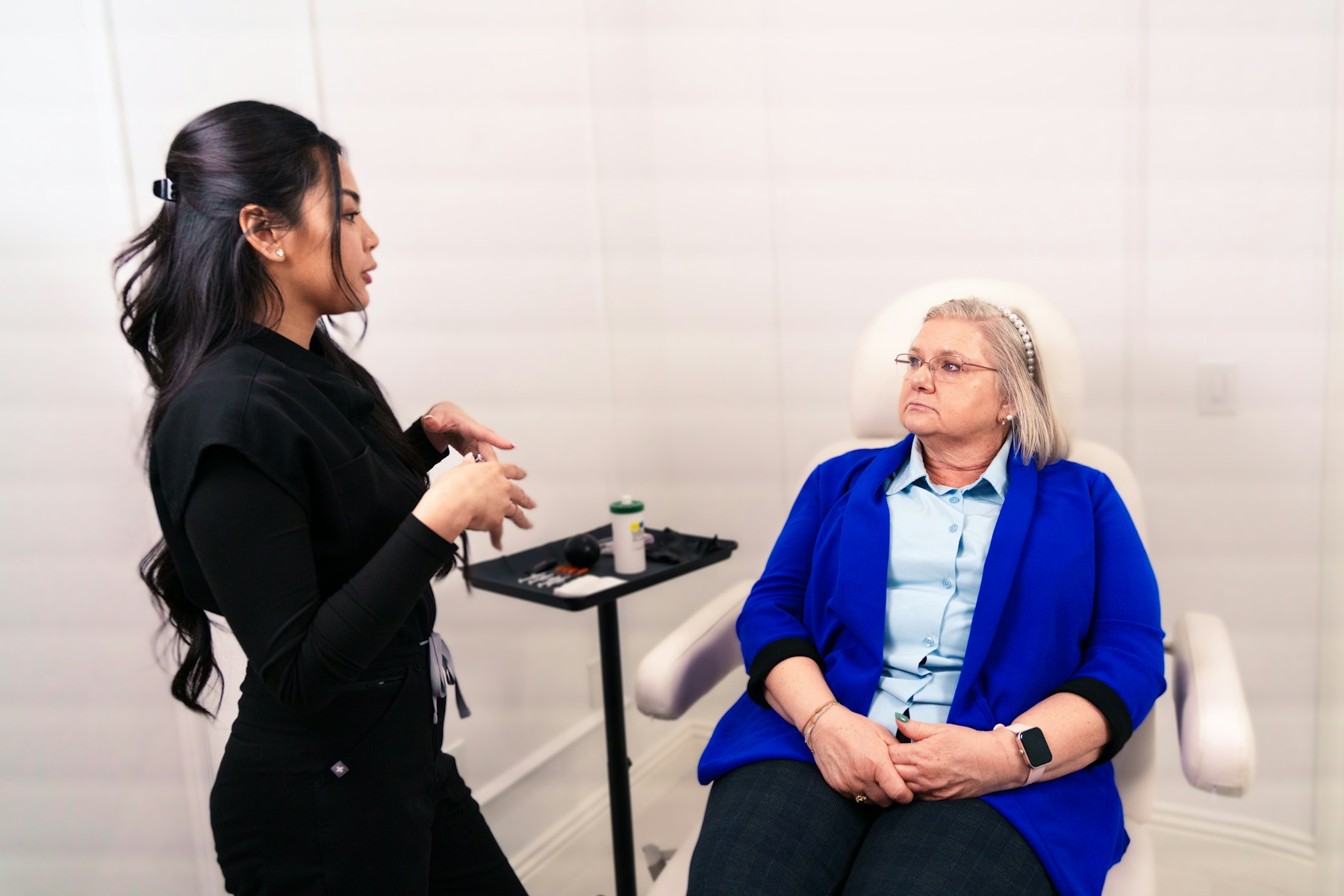 Two women seated in chairs talking during an aesthetic consultation